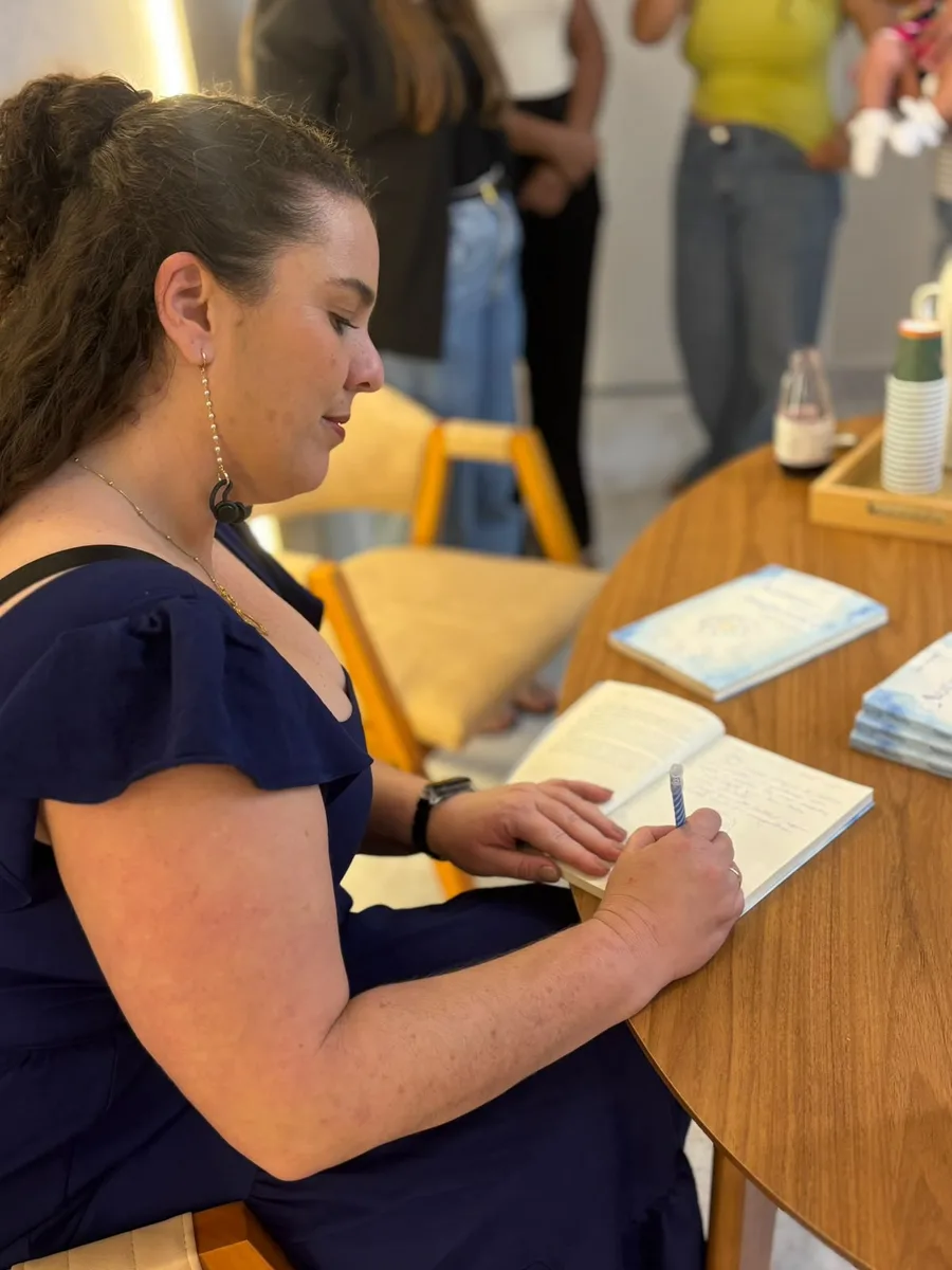 Iaga Vessela autografando um exemplar durante o lançamento do livro